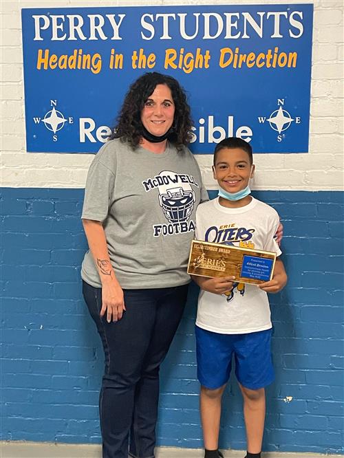 Photo of Perry Stairclimber Elijah Benejan displaying his plaque, adult woman standing at his side.